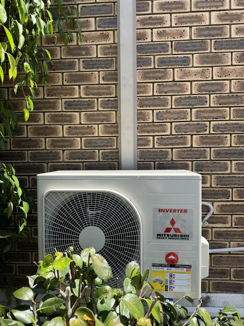 Mitsubishi split system outdoor unit installed against a brick wall