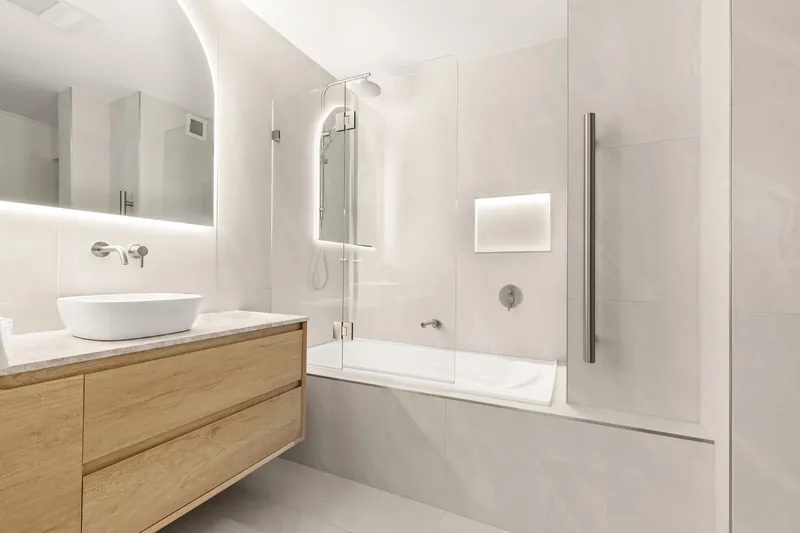 Bathroom with backlit mirror, LED-lit bath niche and heated towel rail