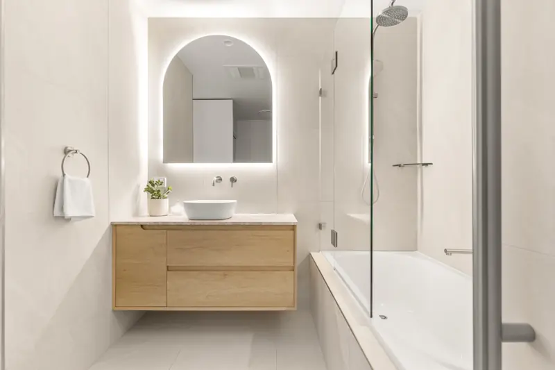 Bathroom with backlit oval mirror and LED-lit bath niche