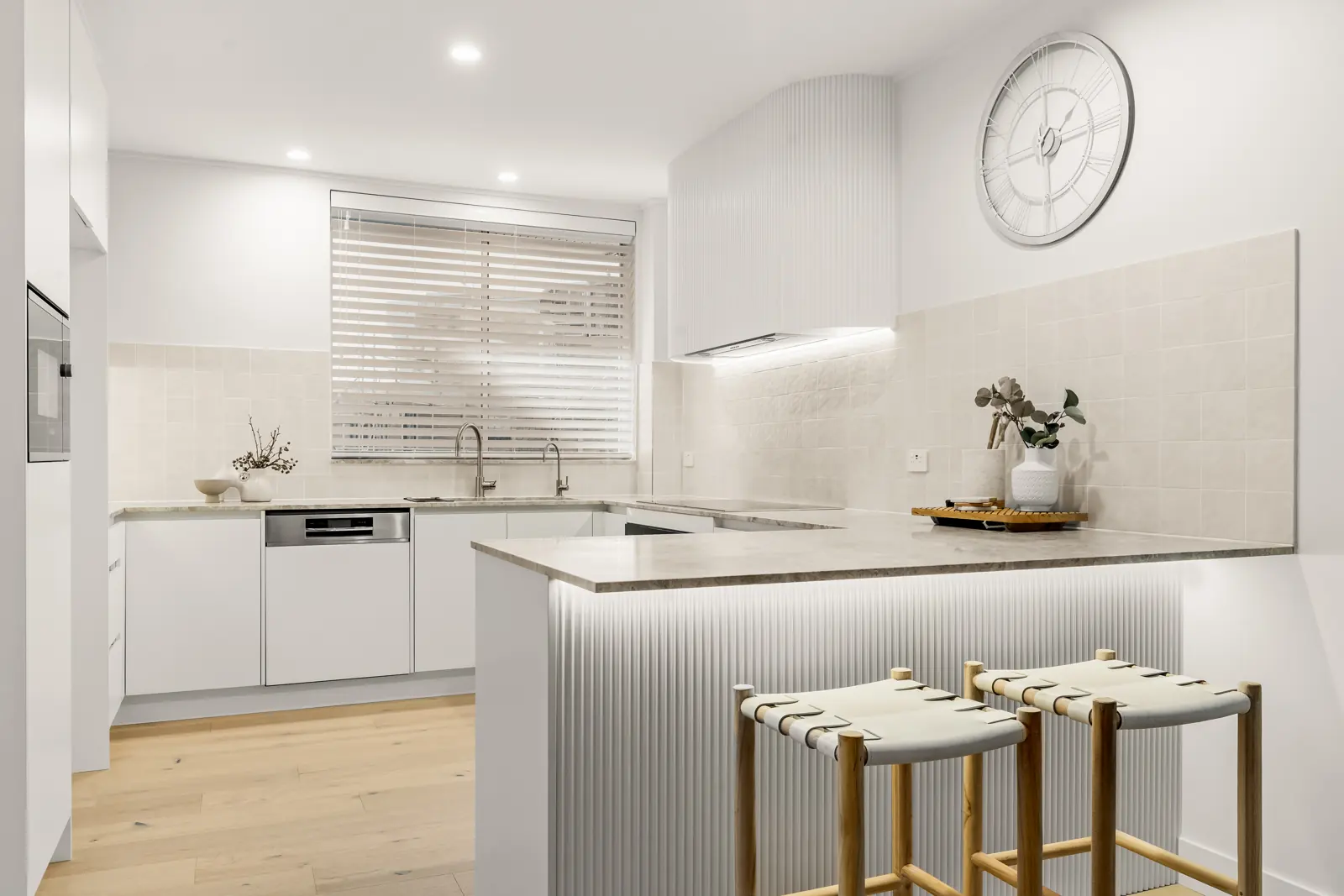 Close-up of LED strip lighting under a fluted kitchen bench, with downlights and rangehood lighting